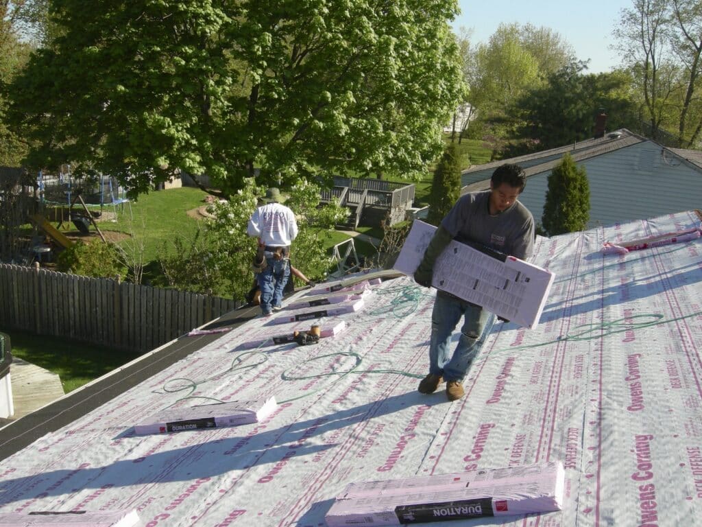 Wonderful Certified East Brunswick Nj Roof Replacents a Man Carrying Bundles of Shingles on Top of a New Roof